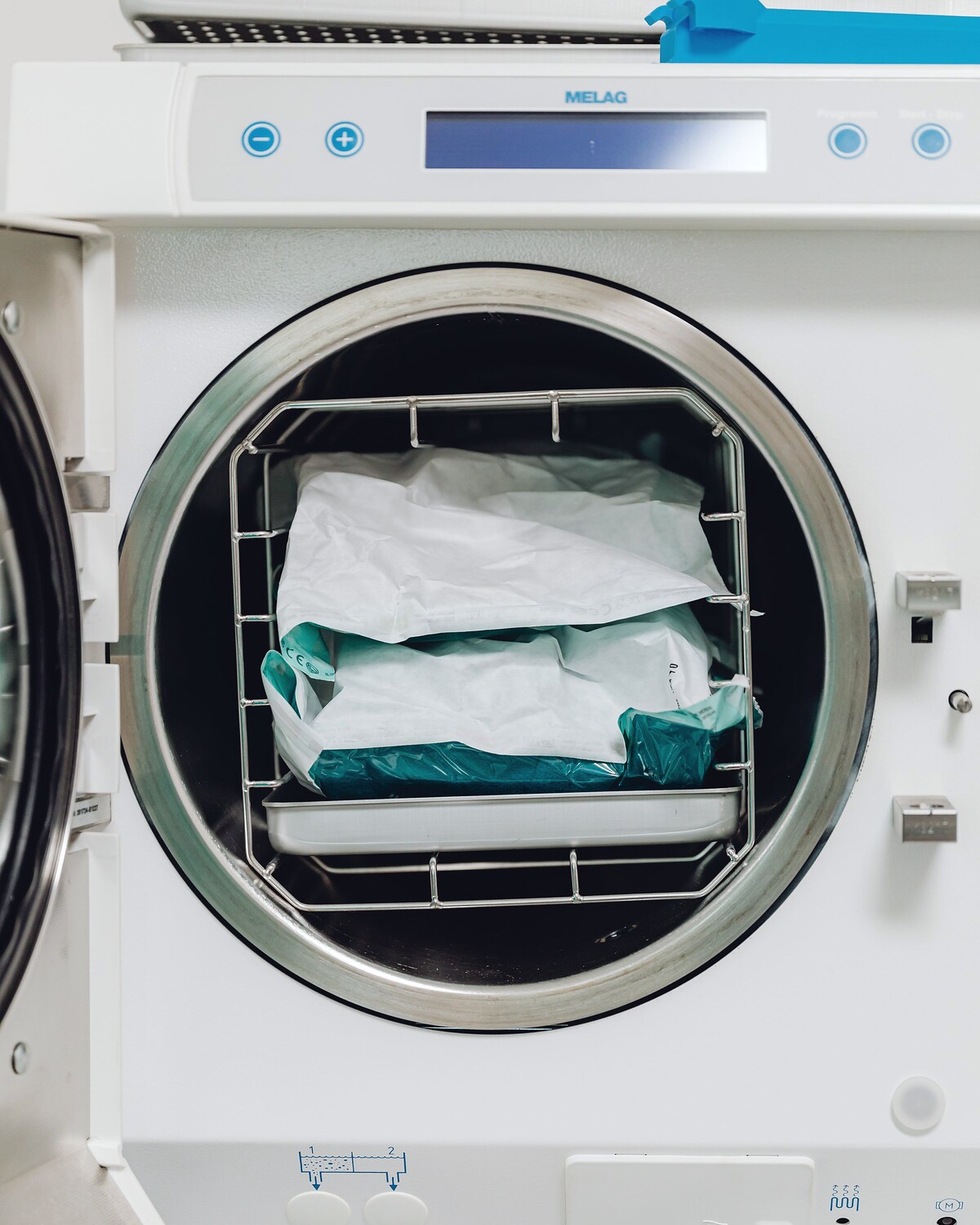 An open autoclave chamber loaded with wrapped sterile packs.