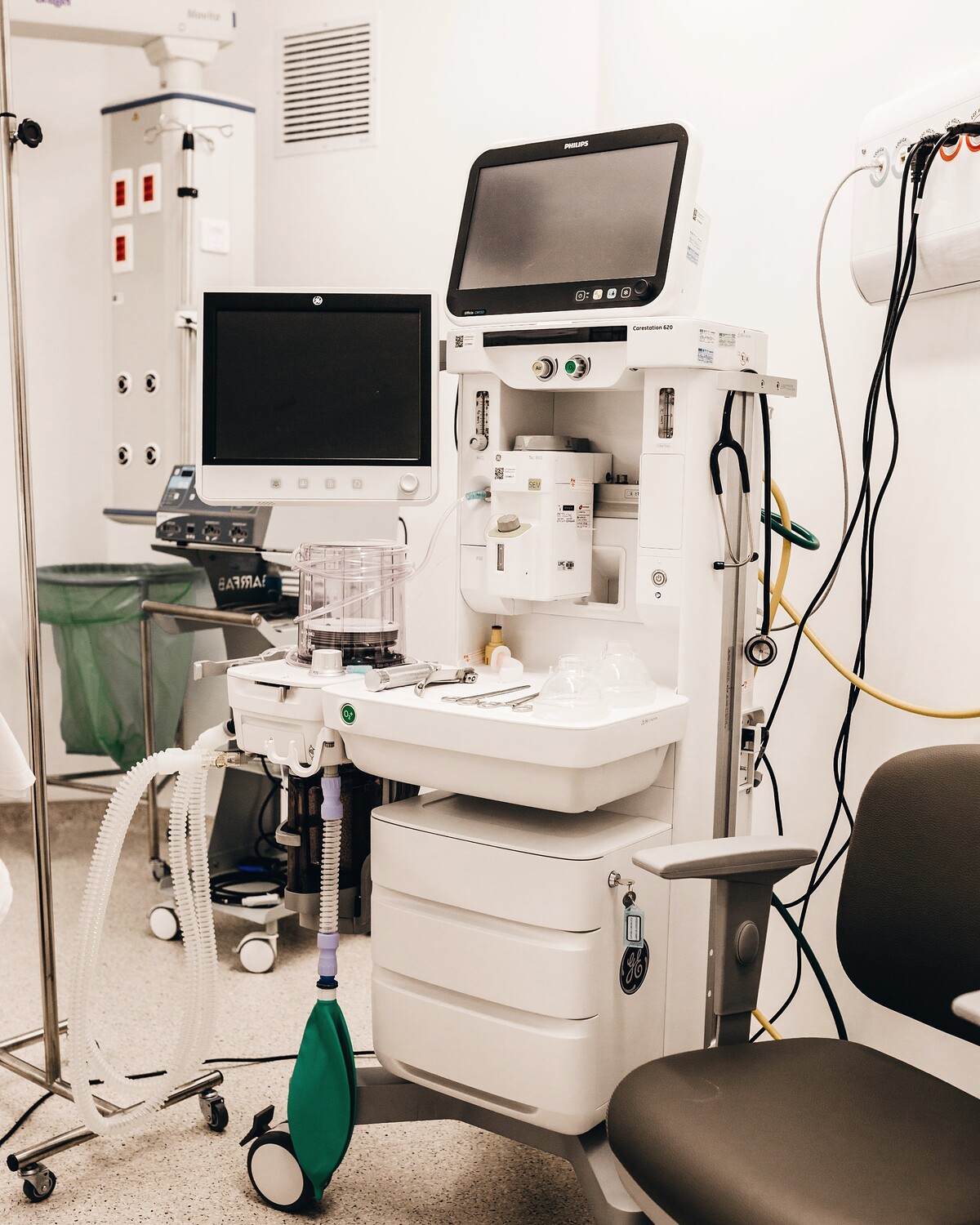 An anaesthesia machine and bedside monitor on a trolley beside a treatment chair.