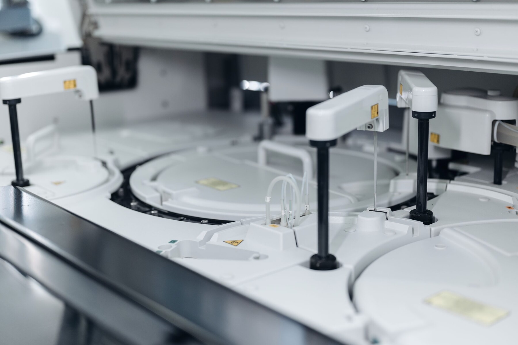 An automated laboratory analyser with sample carousels and pipetting arms.